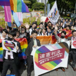 People including plaintiffs’ lawyers hold banners and flags after the lower court ruled that not allowing same-sex marriage was unconstitutional outside Nagoya district court